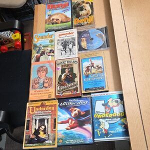 collection of DVDs/VHS/books featuring dog-themed movies & books